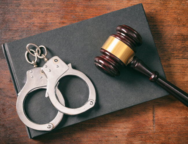 Handcuffs, gavel on book on a wooden background.